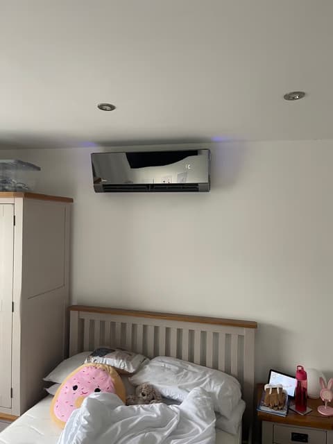 Black mirror-finish air conditioning unit in a bedroom