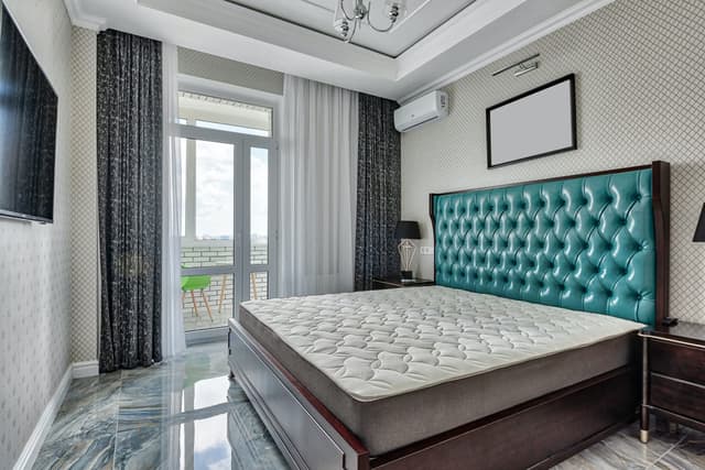 Modern bedroom with a white wall-mounted air conditioning unit above the window
